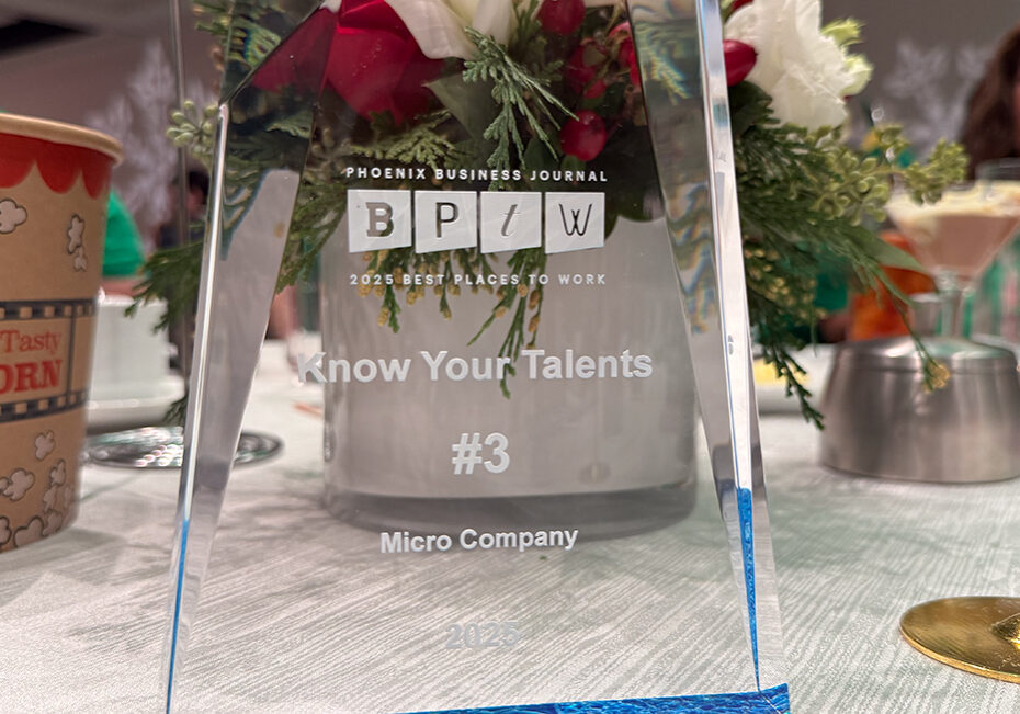Clear geometric acrylic trophy in front of a flower centerpiece. The trophy reads "Phoenix Business Journal 2025 Best Places to Work: Know Your Talents #3 Micro Company 2025"